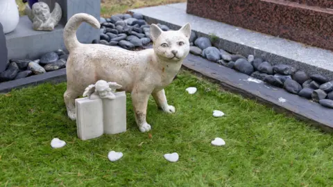 A statue of a cat marking a gravestone in a pet cemetery.