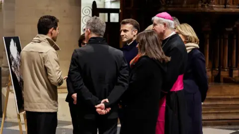 Getty Images Macron was shown around the newly refurbished cathedral alongside Paris's archbishop Laurent Ulrich and Paris mayor Anne Hidalgo