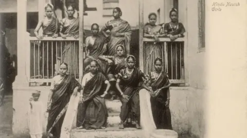 DAG Eleven Hindu Indian women in saris - described as nautch or dancing girls - pose outside a traditional house in this photograph taken by a European photographer somewhere in India in the early 20th century.