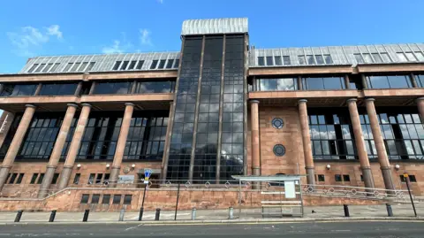 BBC Court building. It is imposing and is made of red bricks, columns and large dark windows