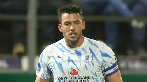 Captain Niall Canavan playing for Barrow on a wild and windy nigh at Holker Street 