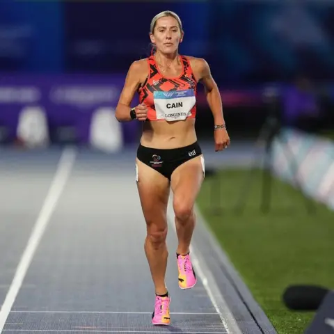 PA Media Christa Cain running in the track wearing the Manx team colours.