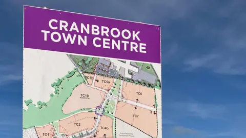 BBC A purple sign with the text 'Cranbrook Town Centre' at the top. Underneath is a map. 