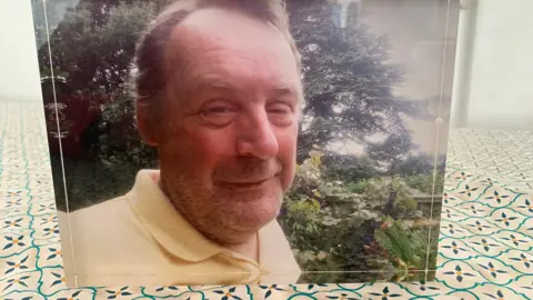 Supplied A family photograph is on display in the family home. Ian Massey is smiling at the camera and is wearing a yellow top. Trees are in the background.