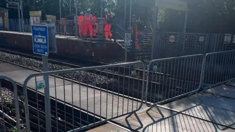 A blocked off tram line with workers milling in the background