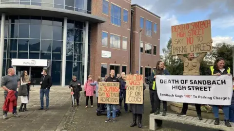 Protestors with signs outside Cheshire East Council's headquarters in Sandbach