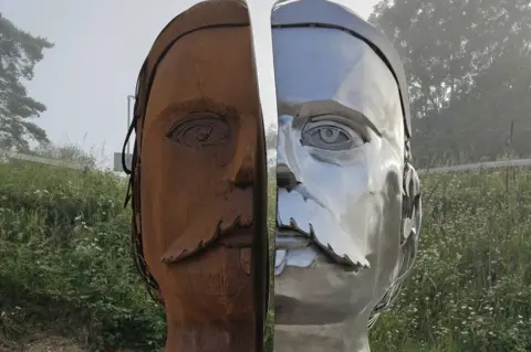 BCP Council Sculpture showing a face in two halves, one side is shiny silver metal, the other is rust