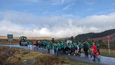 60 young farmers pushing a car uphill
