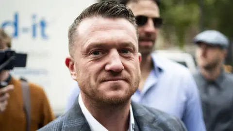 Tommy Robinson - A man wearing a suit looking into the camera