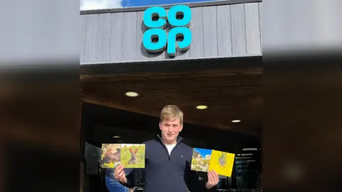 Ben Pulletz Ben outside a Co-op store holding his cards