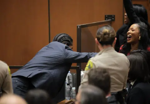 A$AP Rocky leaps over a court barrier to embrace family - a woman cheers and smiles in the background