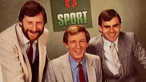 Tony Jones Tony Jones, Gerry Harrison and Stuart Jarrold all wearing suits in an old photograph. They are smiling.