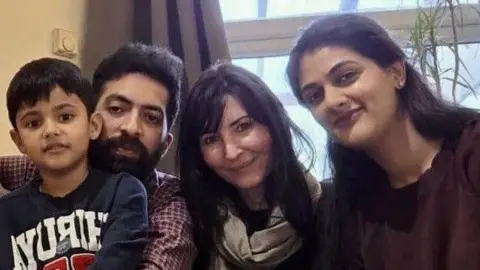 Family handout A young boy with short black hair, sitting beside a man with short black hair and a black beard and two women, both with black hair. 