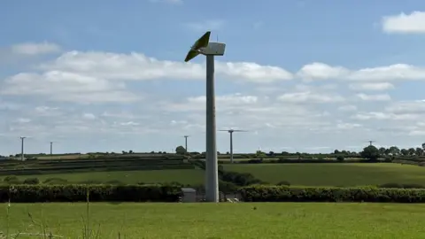 A series of wind turbines on green hills 