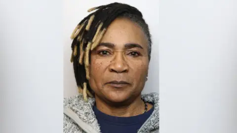 A woman in a mugshot looking seriously at the camera.