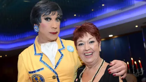 Calon Hearts UK Ceri Dupree dressed as BBC sitcom Hi-de-Hi!'s Gladys Pugh with his arm around actress Ruth Madoc in 2015