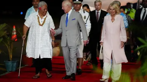 Reuters Britain's King Charles and Queen Camilla are greeted by Samoa's Prime Minister Fiame Naomi Mata'afa as they arrive at Faleolo International Airport in Samoa