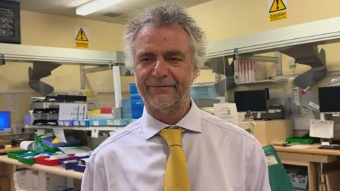 Man stands in front of pharmacy dispensing trays