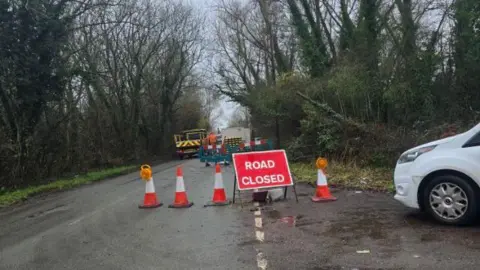 Nigel Harding Road closed sign on a lane with trees either side