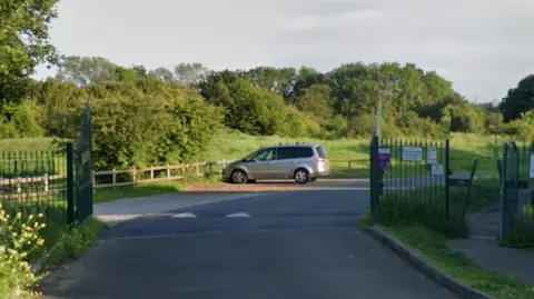 Gated entrance to Wick Country Park. A car park in the middle of green space. 