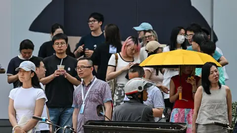 AFP via Getty Images A dozen people stand on the street