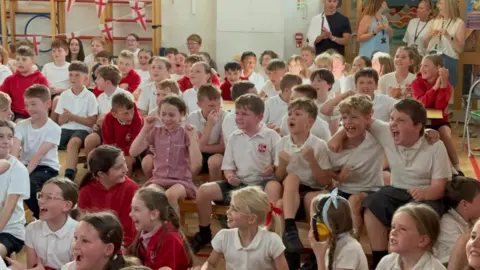 Pupils at Villiers Primary School in Bilston, some in red jumpers, others in white tops with the school badge visible.