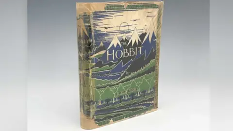 Kinghams Auctioneers The copy of The Hobbit with a partly tattered cover, with blue and black snow-capped mountains 