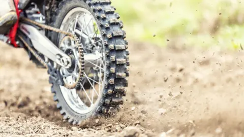The back wheel of a scrambler motorcyle with chain