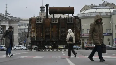 Genya Savilov/AFP People walk past an equipment retrieved from a Ukrainian power plant struck by Russian forces and put on display in the Podil neighbourhood of Kyiv on March 19, 2025.