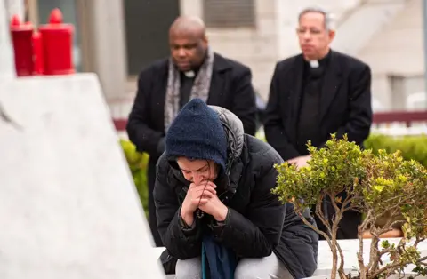 Getty Images People pray in front of the statue of Pope John Paul II outside Rome's Gemelli Polyclinic, where Pope Francis has been hospitalized.
