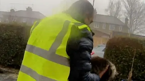 A man in a hi-vis jacket holding a cat
