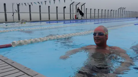 BBC Former Eastenders actor Will Ellis, in the water with goggles and a swimming hat, training at Sea Lanes in Brighton