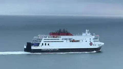 The Manxman, a large white and navy ferry, it is making a journey across a calm sea.