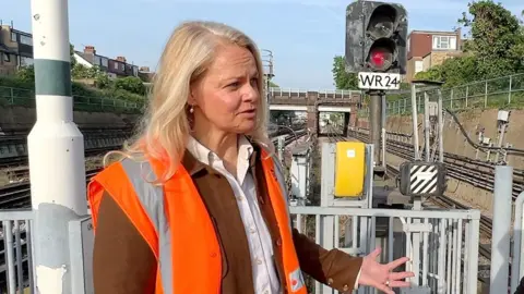 An engineer stands in front of a signal and tube tracks in hi-vis