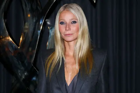 Getty Images Gwyneth Paltrow looking at camera at a red carpet event. She wears a navy blazer dress and has long blonde hair. 