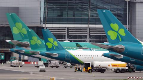 Aeroplanes with a shamrock on the end of the aircraft, parked on airport grounds 