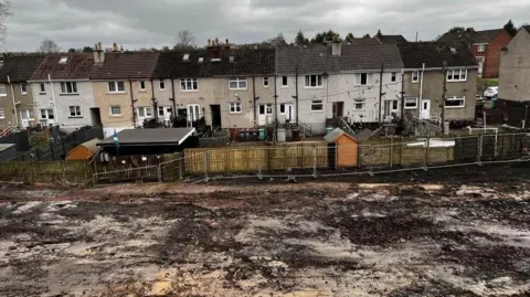 A blasted heath behind some houses