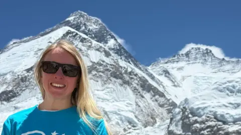 Rowena standing and smiling at the camera with Mount Everest behind her
