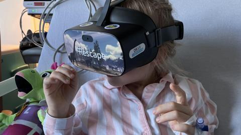 Girl, 8, in stripy pink pyjamas wearing the virtual reality headset