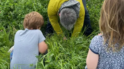 Lucy Noad Two children with an adult observing the soil in a field