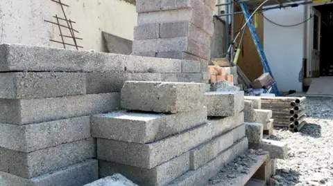 A stack of grey bricks on a pallet at a building site.