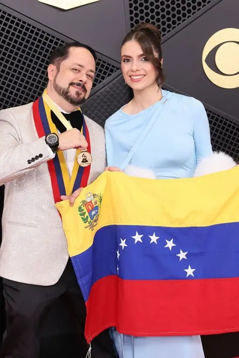 Getty Images Raniero Palm holds a Venezuelan flag as he poses on the red carpet with Mariana Salas