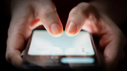 Getty Images fingers tapping on a smartphone screen. 