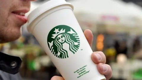 Getty Images Man drinking out of Starbucks cup.