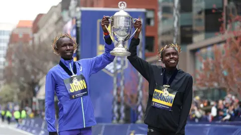  John Korir and Sharon Lokedi hold up the Boston Marathon trophy