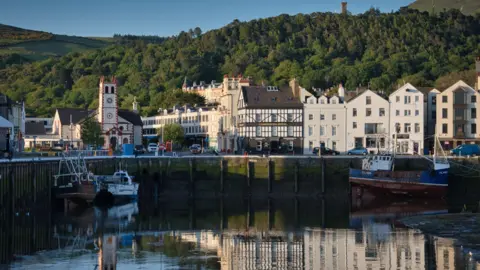 Manx Scenes Ramsey harbour overlooking the water, with hills and trees in the background.