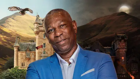 BBC/Studio Lambert A publicity head-and-shoulders photo of Keith, a man with short hair and wearing a blue blazer and a white shirt. Behind him is the traitors castle.