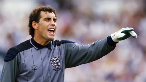 David Cannon/Allsport/Getty Images Peter Shilton playing for England in the 1986 World Cup. He is wearing a grey kit and pointing while giving instructions to a teammate.