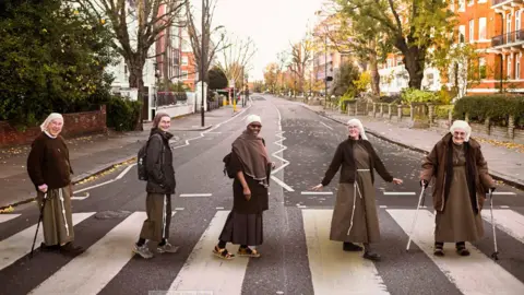 Dave Meyer The Poor Clares of Arundel, posing on the iconic zebra crossing outside Abbey Road Studios, dressed in their nun's habits