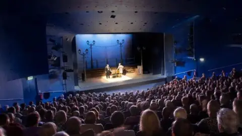 Derby Theatre A theatre full of people watching a play
